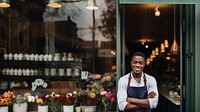 Photo of a cheerful small business owner standing and smiling in front of their shop.  