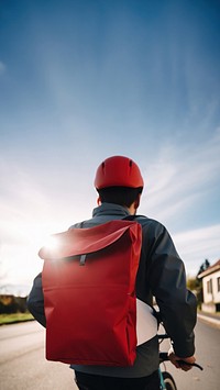 photo of a delivery rider wearing color jacket back view with white plain bag on a bike.  