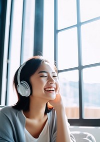 Photo of Asian woman smiling at home in headphones.  