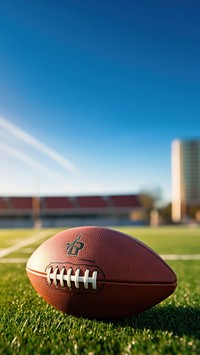 photo of Close-up of American Football on Grass Field with Blurry Stadium in Background. AI generated Image by rawpixel.