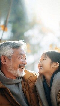 photo of Smiling happy older asian father with stylish short beard touching daughter's hand on shoulder looking and talking together.  