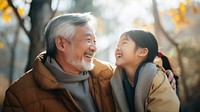 photo of Smiling happy older asian father with stylish short beard touching daughter's hand on shoulder looking and talking together.  