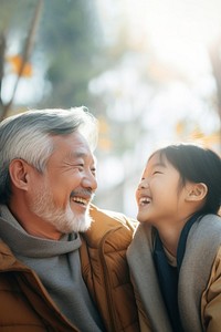 photo of Smiling happy older asian father with stylish short beard touching daughter's hand on shoulder looking and talking together.  