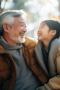 photo of Smiling happy older asian father with stylish short beard touching daughter's hand on shoulder looking and talking together.  