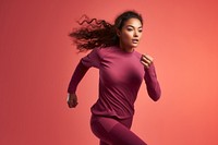 Woman running in athletic wear against a coral background. Fitness and athleticism are highlighted as she runs. Sporty and energetic scene.