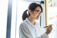 photo of asian women wearing glasses writing a chart on a whiteboard. AI generated Image by rawpixel.