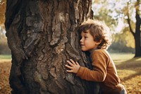 Little boy hugging a tree. 