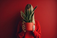 Woman holding a potted plant face red houseplant. 