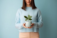 Woman holding a potted plant sweater sweatshirt blue. AI generated Image by rawpixel.
