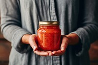 Sauce jar holding food hand. 