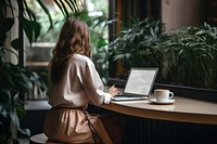 Woman sitting at a table with a laptop coffee furniture computer. AI generated Image by rawpixel.