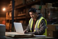 Middle age asian male warehouse worker checking orders at computer workstation laptop adult concentration. 