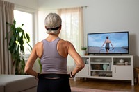 Mature woman watching and copying exercises with a resistance band in her living room television screen adult. 