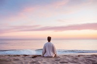 Man wearing white meditating on the beach sea sky outdoors. AI generated Image by rawpixel.