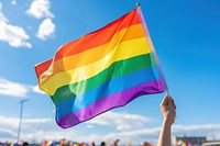 Hand holding a colorful rainbow gay flag parade pride sky. AI generated Image by rawpixel.