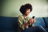 Happy relaxed young woman using cell phone laughing sitting holding. AI generated Image by rawpixel.