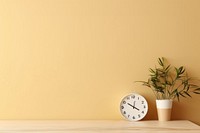 Wooden white table with plant and small clock on beige wall yellow architecture houseplant. AI generated Image by rawpixel.