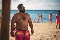 Fat Latino man in a swimming pants and tank top walking on the beach sunglasses vacation portrait. 