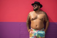 Plus size Latino man in a swimming pants standing in front of a colorful wall fashion tattoo adult. AI generated Image by rawpixel.