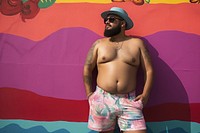 Plus size Latino man in a swimming pants standing in front of a colorful wall vacation fashion adult. AI generated Image by rawpixel.