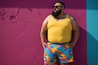 Plus size Latino man in a swimming pants standing in front of a colorful wall glasses fashion shorts. AI generated Image by rawpixel.
