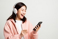 Asian teenage girl streaming online music on mobile phone headphones laughing headset. 