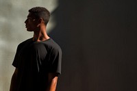 A man in a oversize black t shirt portrait t-shirt shadow. AI generated Image by rawpixel.