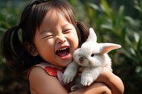 Photo of Chinese little girl holding a little rabbit in her arms and laughing happiness portrait mammal. AI generated Image by rawpixel.