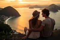 Two Latin Brazilian tourists sitting happily on a hill sea outdoors nature. 