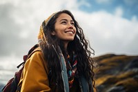 A Latina Mexican female backpacker sitting and gazing happily at the sky in Alaska travel nature smile. 