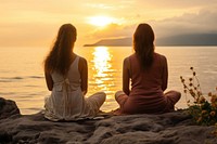 Female friends sitting in a lotus pose meditating outdoors beach. AI generated Image by rawpixel.