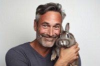American middle age man hugging rabbit portrait animal mammal. AI generated Image by rawpixel.
