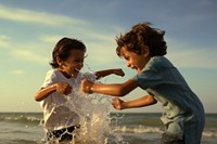 Latina brazillian boy splash water to his brother outdoors summer beach. AI generated Image by rawpixel.