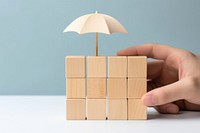 Hand holding umbrella wood block cover Insurance icon toy sheltering protection. AI generated Image by rawpixel.