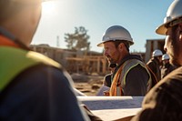 Close-up of a construction worker holding architectural plans and discussing with colleagues at a construction site discussion planning hardhat. AI generated Image by rawpixel.