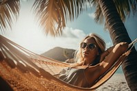 A blonde hair woman sleeping in a hammock under the coconut tree on the beach vacation glasses adult. AI generated Image by rawpixel.