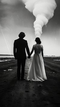 A wedding couple holding hand while the tornado at the background photography silhouette outdoors. 