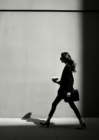A city woman having a sandwich while walking to work photography silhouette footwear. 