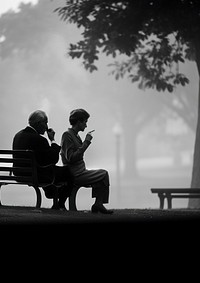 A woman smoking sitting next to an elder man smoking cigarrette in the park outdoors black white. AI generated Image by rawpixel.
