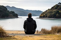 Man with black sweater sitting outdoors nature. 