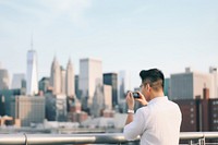 Chinese man using smartphone with headphones on rooftop adult photo architecture. 