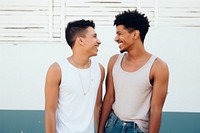 Latinx Two happy smiling friends from lgbt community standing looking at each other together laughing togetherness affectionate. 