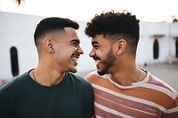 Latinx Two happy smiling friends from lgbt community standing looking at each other together laughing adult togetherness. 