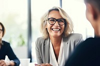 Mature businesswoman wearing eyeglasses laughing during meeting at office adult smile conversation. AI generated Image by rawpixel.