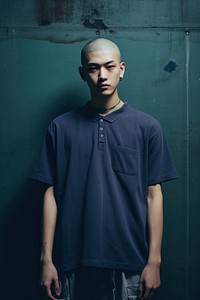 Asian teen man have skinhead in a blue and black short shirt standing against a grey background portrait t-shirt sleeve. AI generated Image by rawpixel.