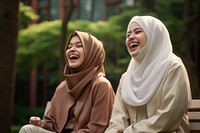 Women in hijab laughing on a bench in the park adult togetherness celebration. AI generated Image by rawpixel.