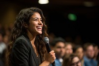 Young Hispanic woman speaker on professional stage in meeting microphone audience smiling. AI generated Image by rawpixel.