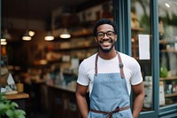 A multiracial man standing in front of a bookshop smiling working glasses. 