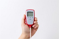 A close up photo of a hand holding a glucose monitor cyclocomputer thermometer electronics. AI generated Image by rawpixel.