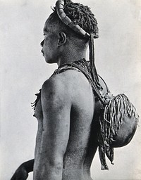 An African man carrying a round container supported by shoulder straps on his back. Photograph, ca. 1900.